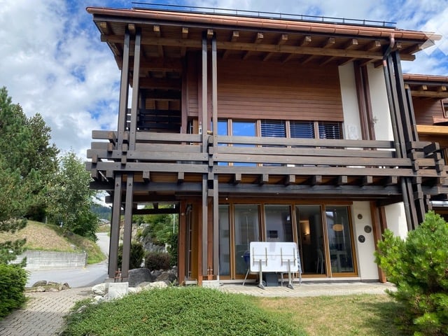 Modern two-story wooden building with large windows, balconies, and a covered entrance area.