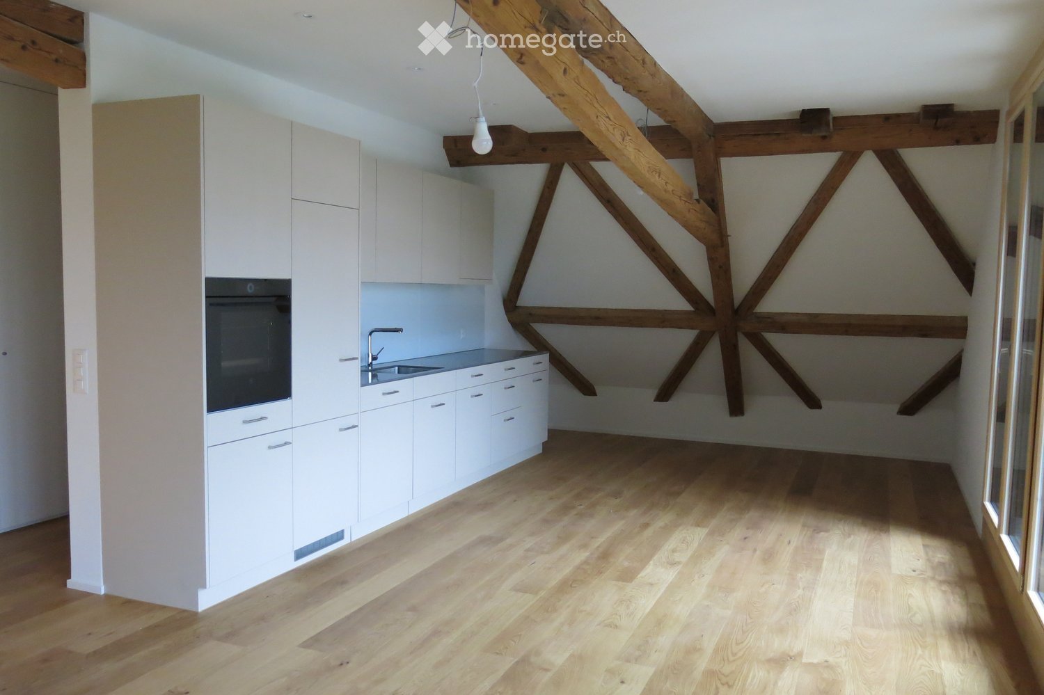 Kitchen. Modern kitchen with white cabinets, wooden floor, exposed wooden beams, and a sink with a faucet.