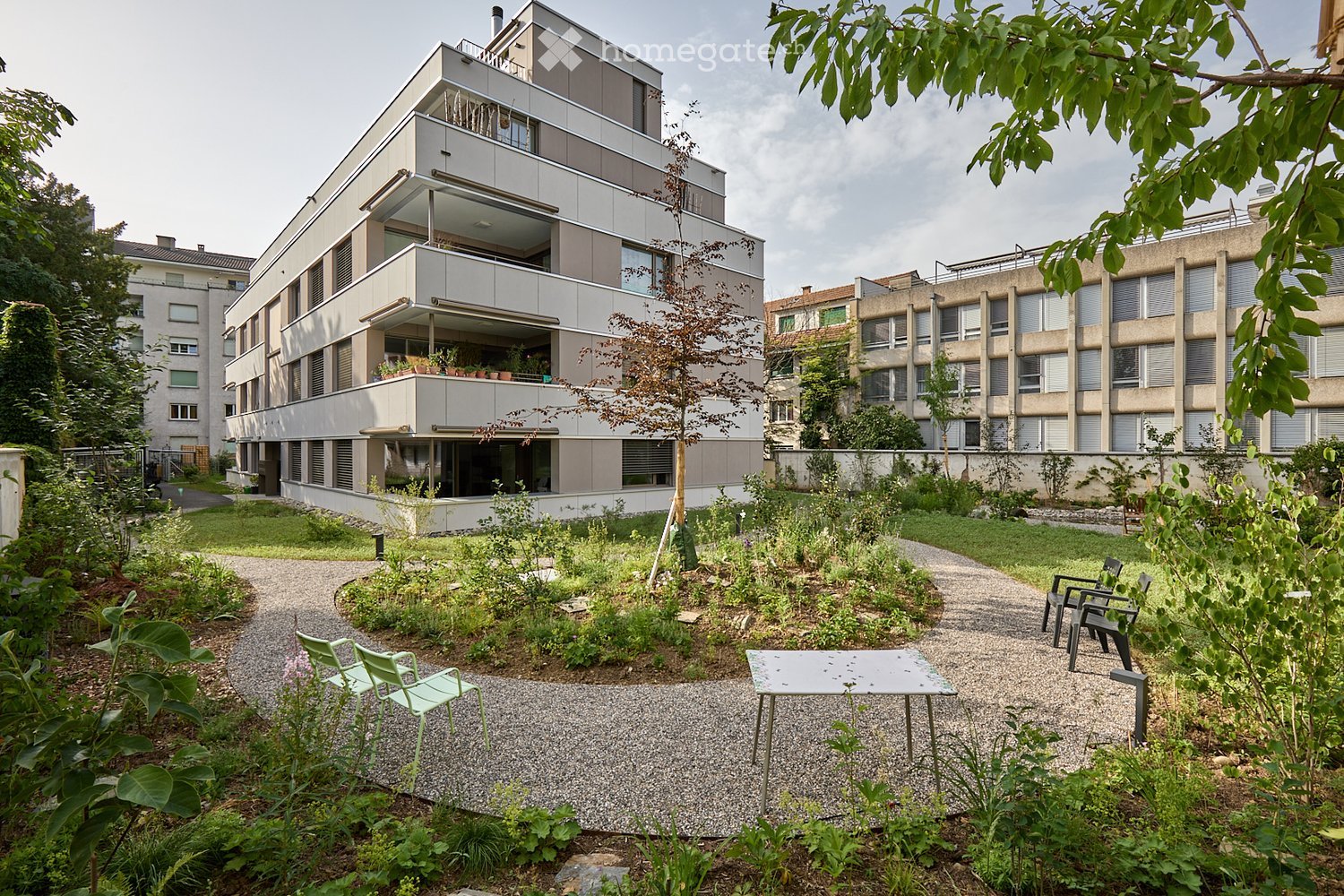 Garden area with gravel path, greenery, and outdoor furniture including a table and chairs.