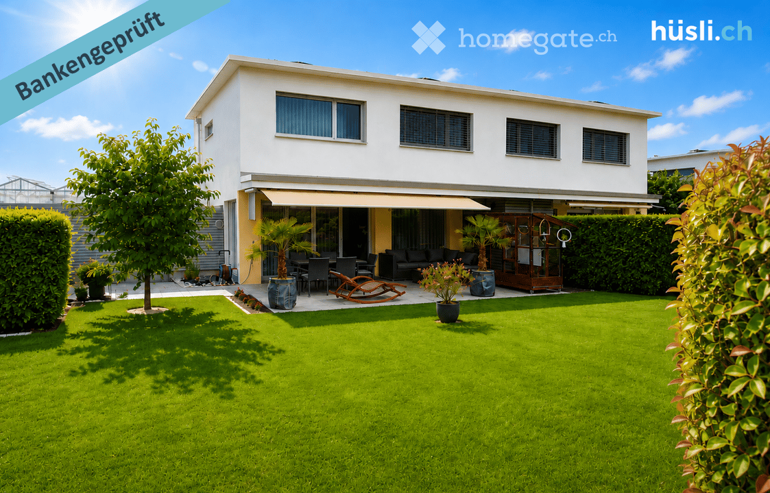 Well-maintained garden with a modern house in the background, featuring a patio with outdoor furniture, potted plants, and a neatly trimmed lawn.