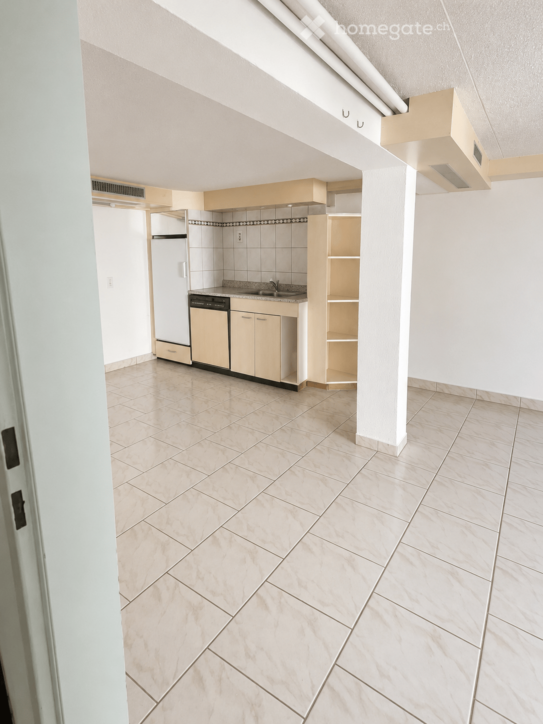 Modern kitchen with light-colored cabinets, a refrigerator, dishwasher, and a sink, featuring tiled walls and a tiled floor.