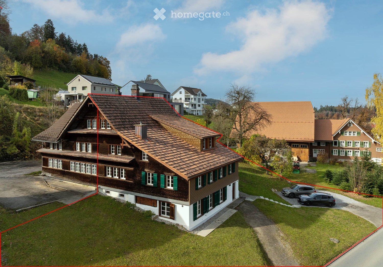 wooden house, brown roof, green window shutters, driveway, 2 parked cars