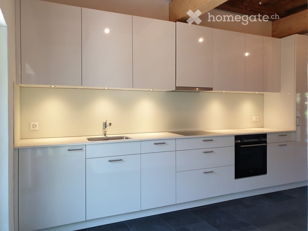 Modern white kitchen with sleek cabinets, a stainless steel sink, and built-in oven.