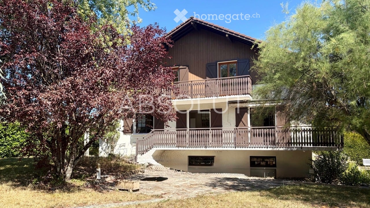 Two-story house with wooden exterior, multiple balconies, and a staircase leading to the main entrance.