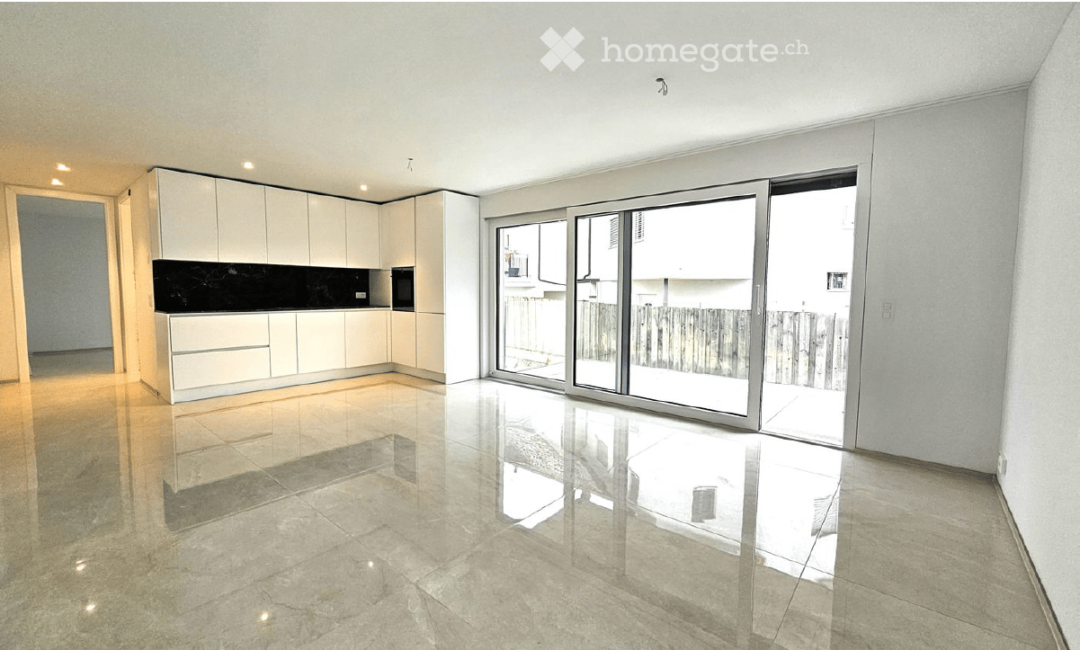 Modern, unfurnished kitchen with white cabinetry, a black countertop, and large sliding glass doors leading to a balcony.