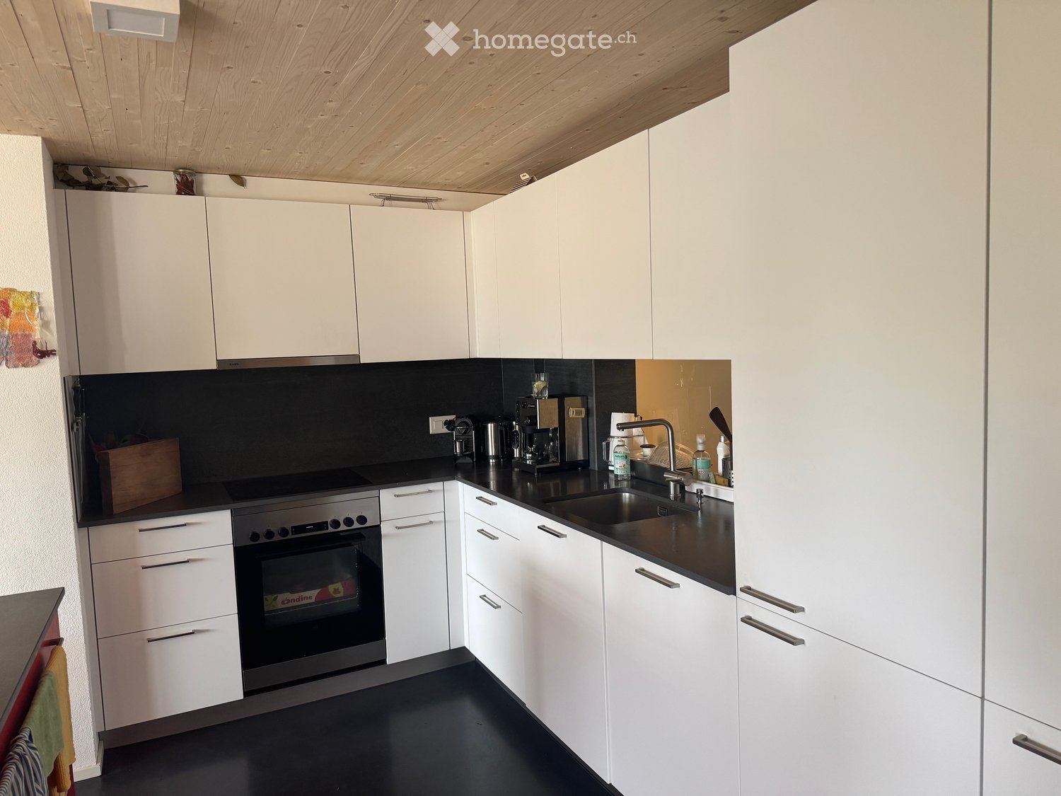 Modern kitchen with white cabinets, black countertops, and stainless steel appliances, including an oven and a sink.