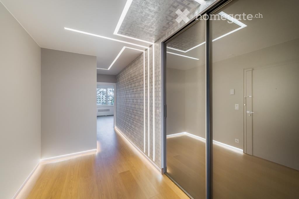 Modern hallway with wooden flooring, recessed lighting, and glass doors leading to adjacent rooms.