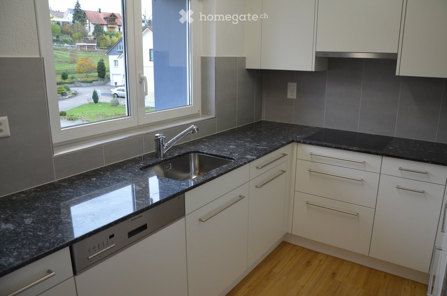Modern kitchen with white cabinets, granite countertops, stainless steel sink and faucet, and built-in dishwasher.