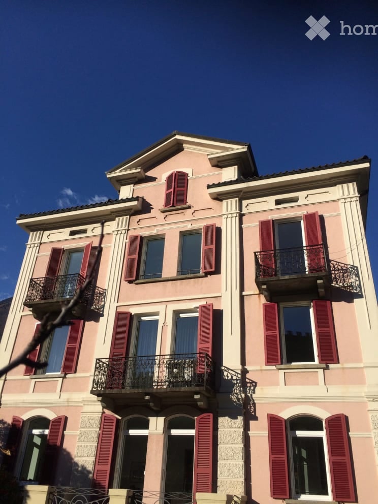 Pink building with multiple floors, red shutters, and balconies.