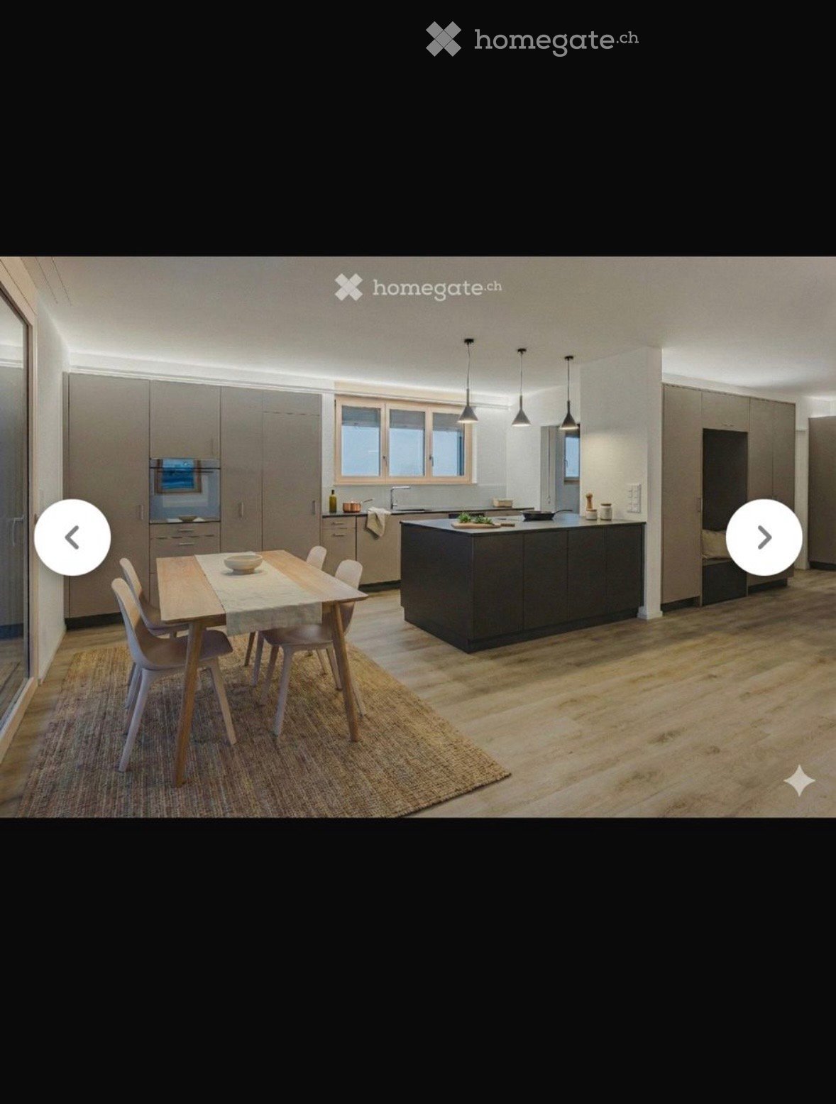 Modern kitchen with a central island, dining table, and chairs, featuring built-in cabinets and appliances.