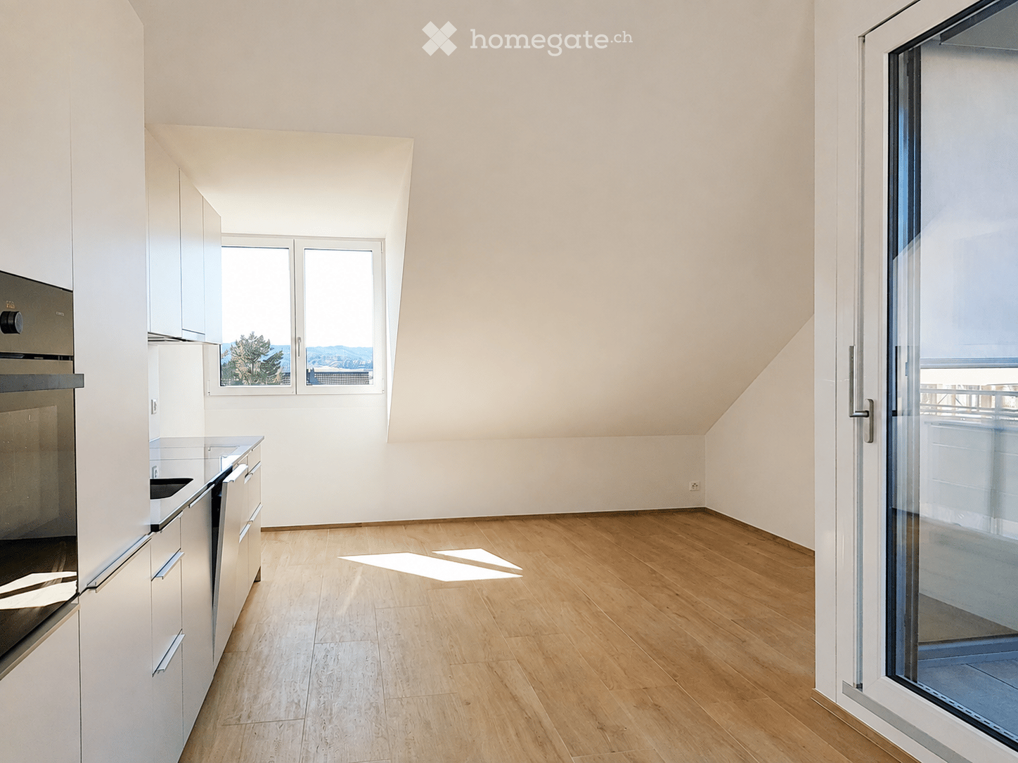 Modern kitchen with white cabinets, wooden flooring, and large windows offering a scenic view.
