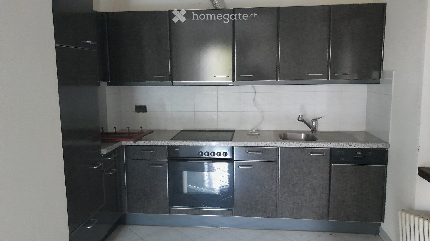 Modern kitchen with dark grey cabinets, stainless steel appliances, and a granite countertop.