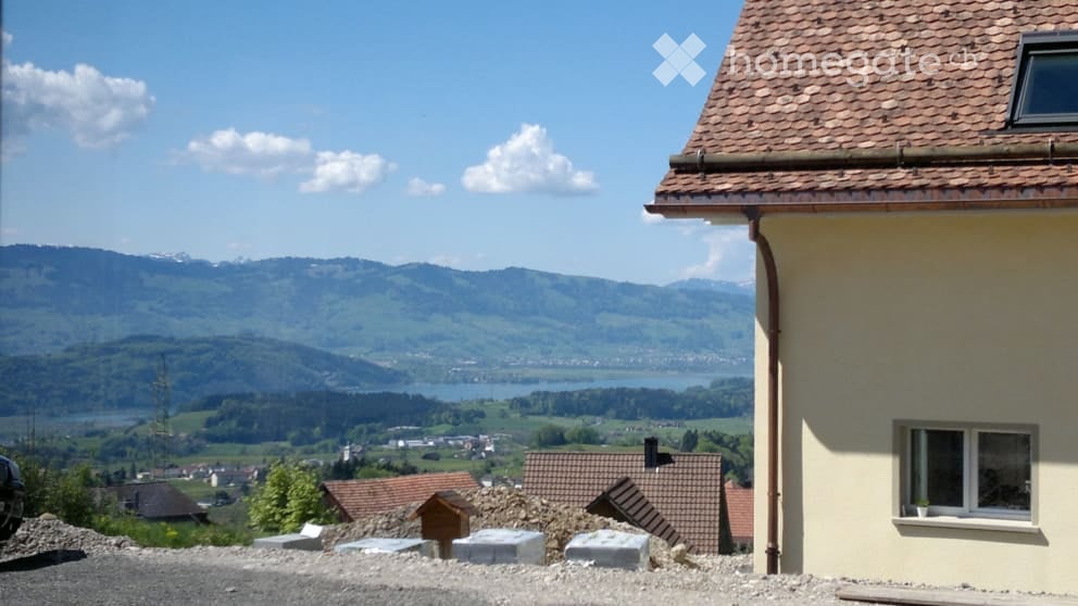 Building. View of a house with a tiled roof and a scenic mountain and lake backdrop.