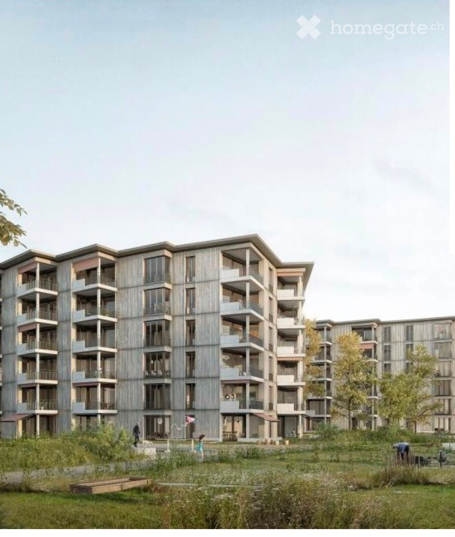 Modern multi-story residential building with balconies and large windows, surrounded by green space and trees.