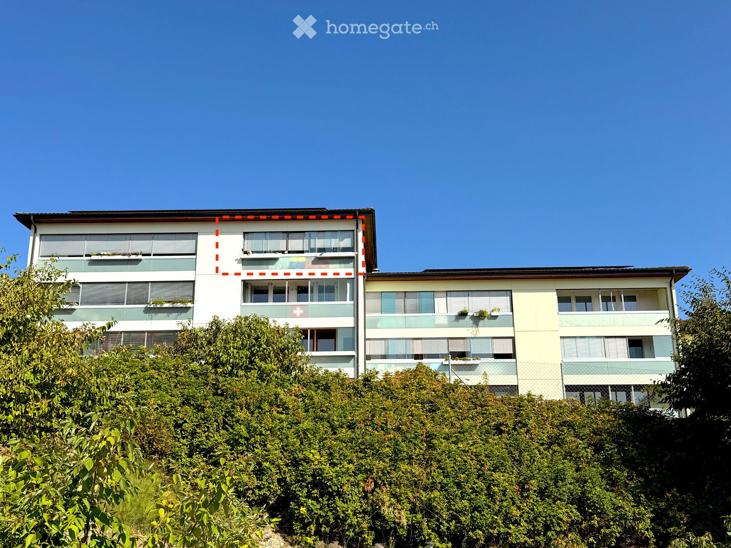 Modern multi-story residential building with white and light blue facade, large windows, balconies, and greenery in front.