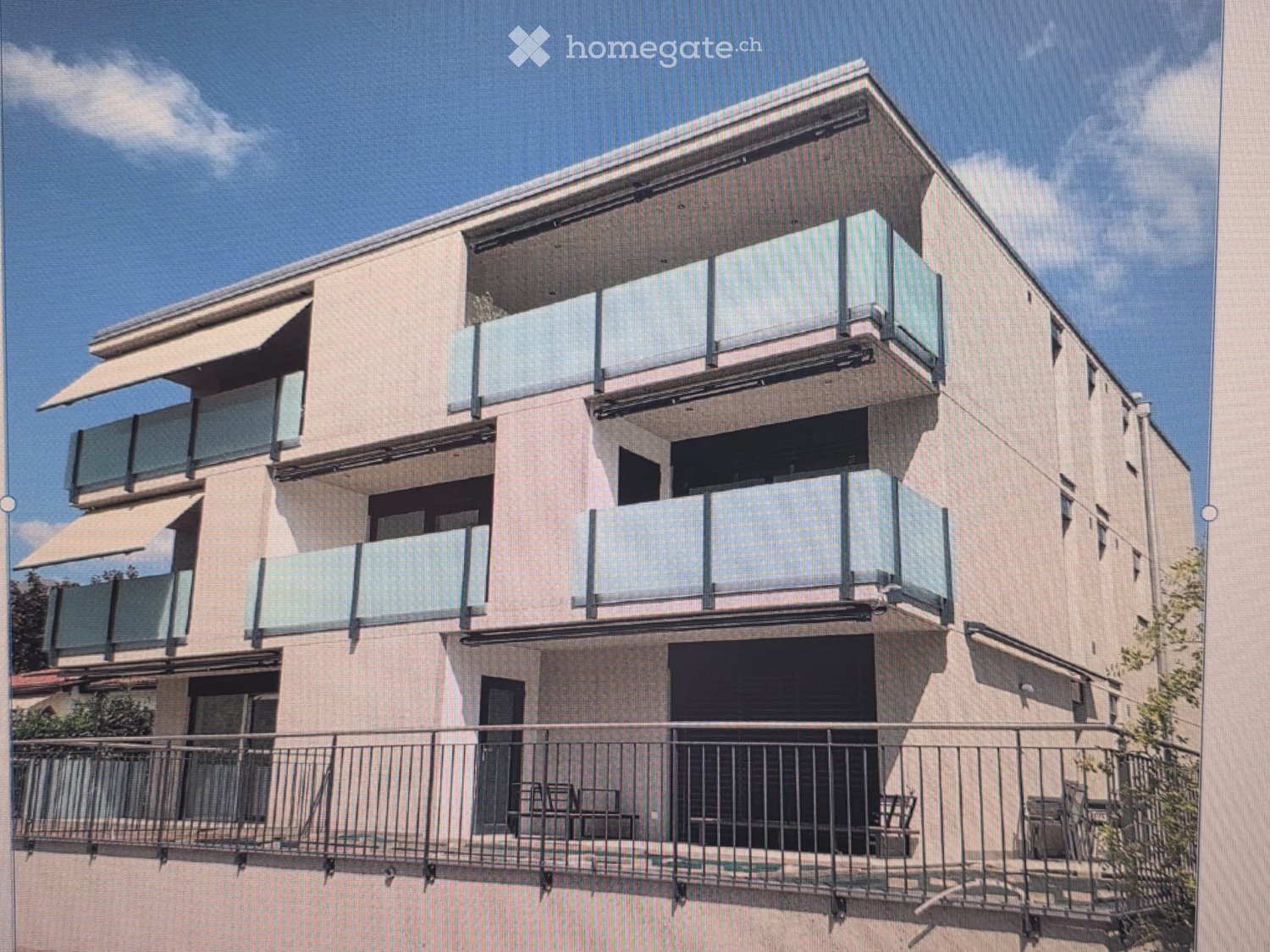 Modern multi-story building with balconies, large windows, and awnings, featuring a contemporary design with clean lines and a neutral color palette.