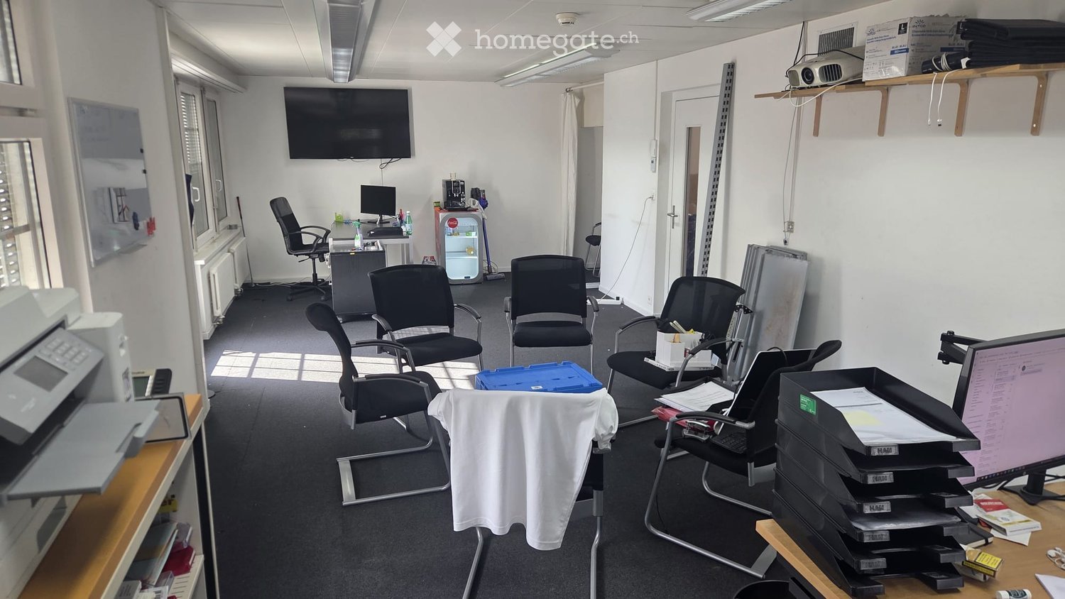 Office space with multiple chairs, a desk, a screen, a printer, and a small refrigerator.