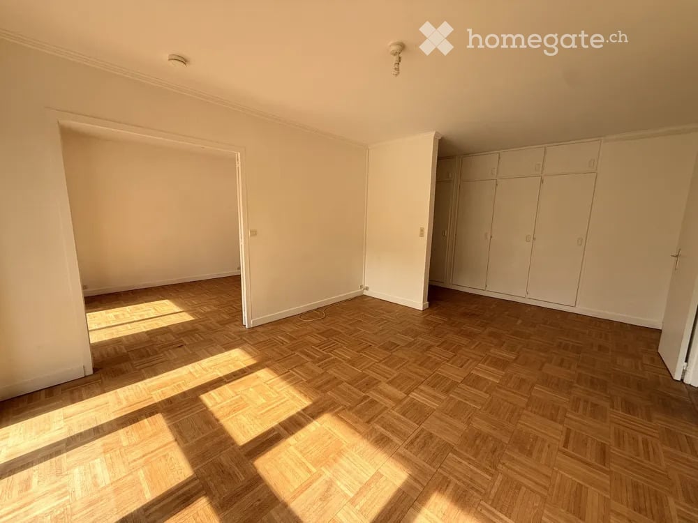 Empty room with wooden parquet flooring, white walls, and built-in wardrobes. No furniture or personal items present.