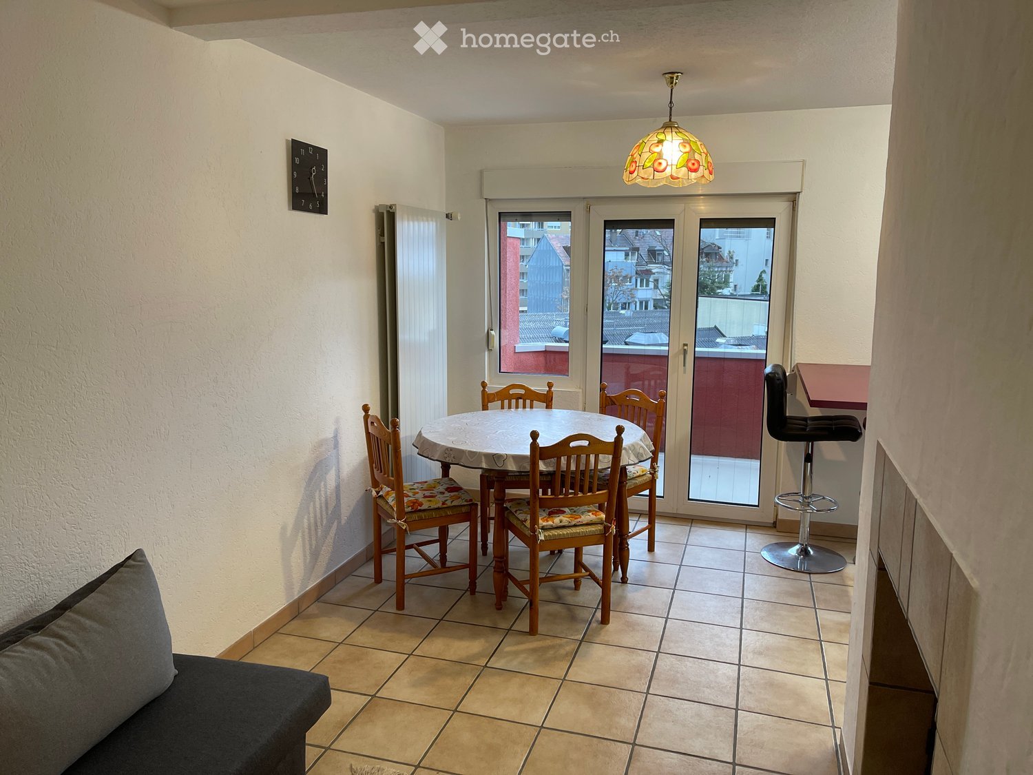 4 chairs, table, dining table cover, tiled floor, decorative lamp, clock on wall, sliding glass doors, fireplace