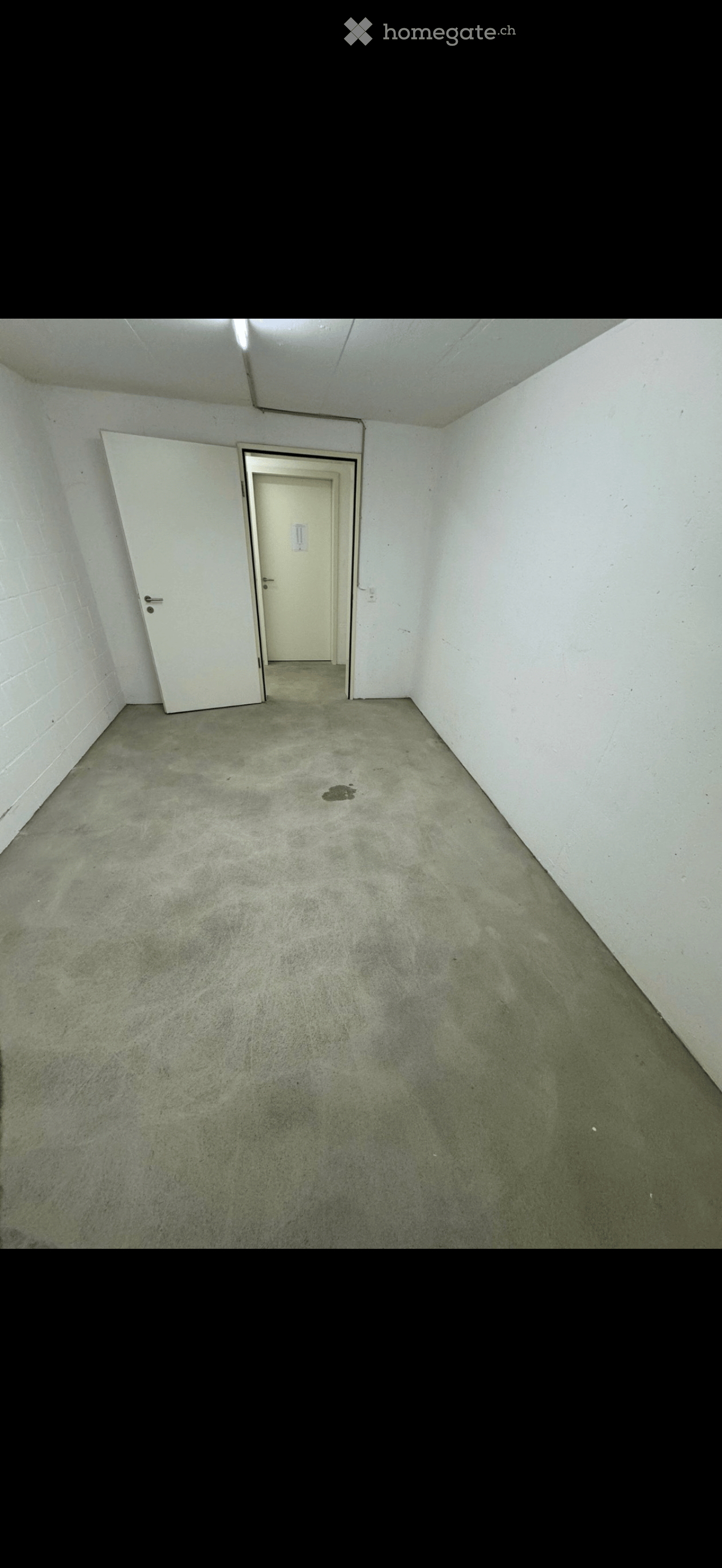 Empty room with concrete floor, white walls, and two doors.