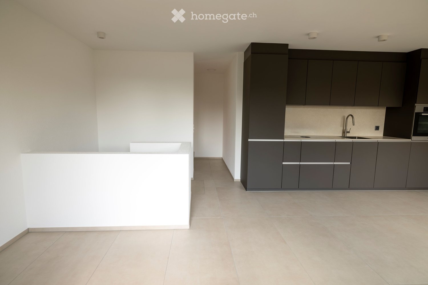 Modern kitchen with grey cabinets, a white island, and a stainless steel sink and faucet.