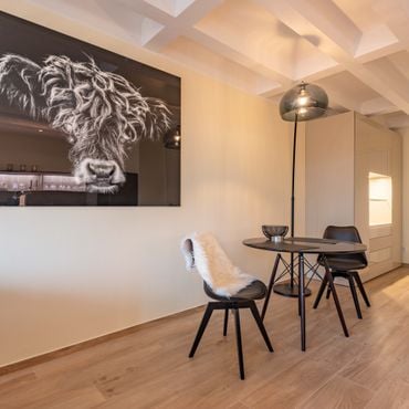 Modern dining area with a sleek black table, four chairs, a floor lamp, and a large black-and-white animal portrait on the wall.