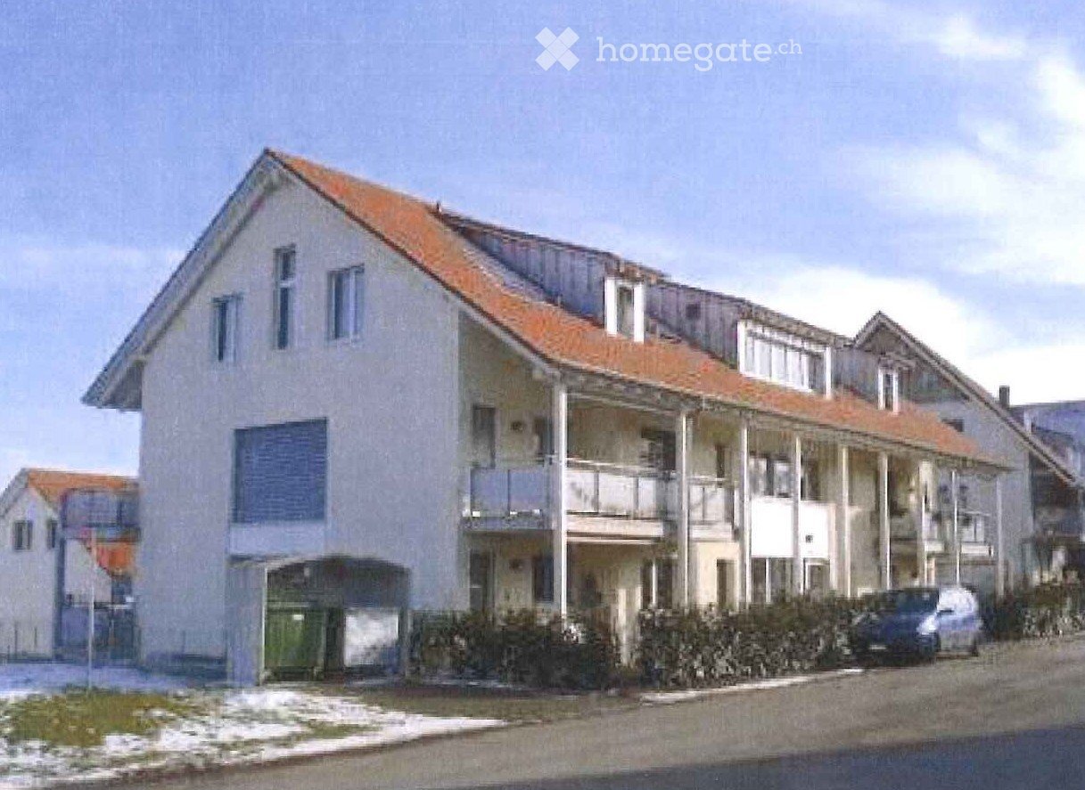 Two-story house with a red-tiled roof, multiple windows, and a covered balcony area on the upper floor.