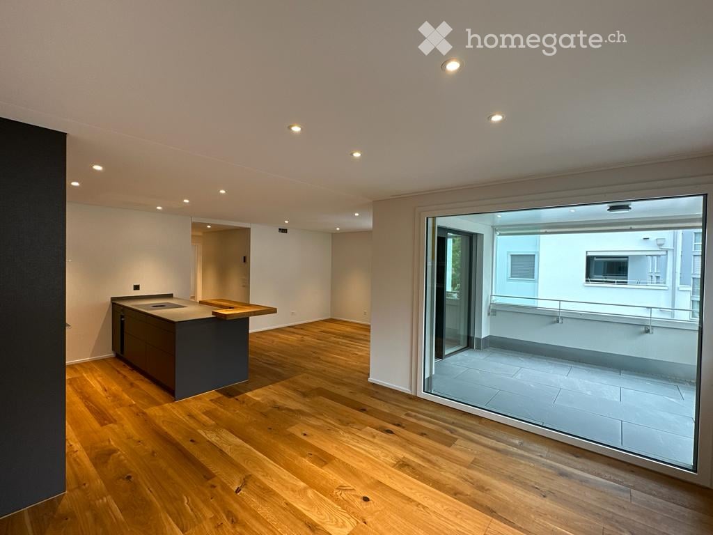Modern kitchen with wooden flooring, a kitchen island, and a large sliding glass door leading to a balcony.