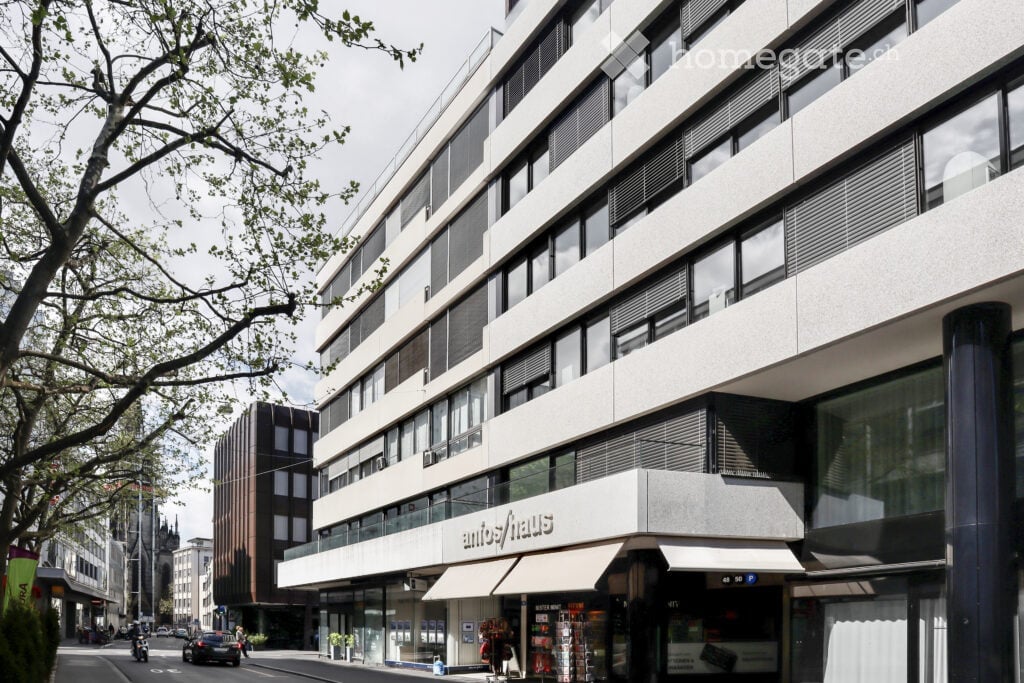 Modern multi-story building with large windows and a sign reading "antifhaus" on the ground floor.