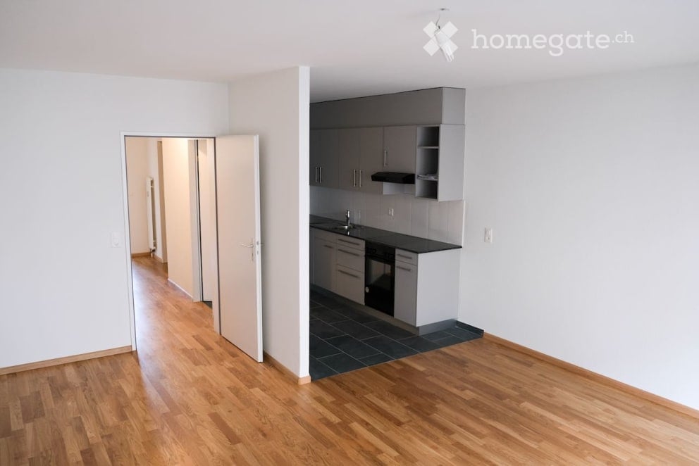 Empty room with wooden flooring, white walls, and a doorway leading to another space. No furniture or equipment is present.