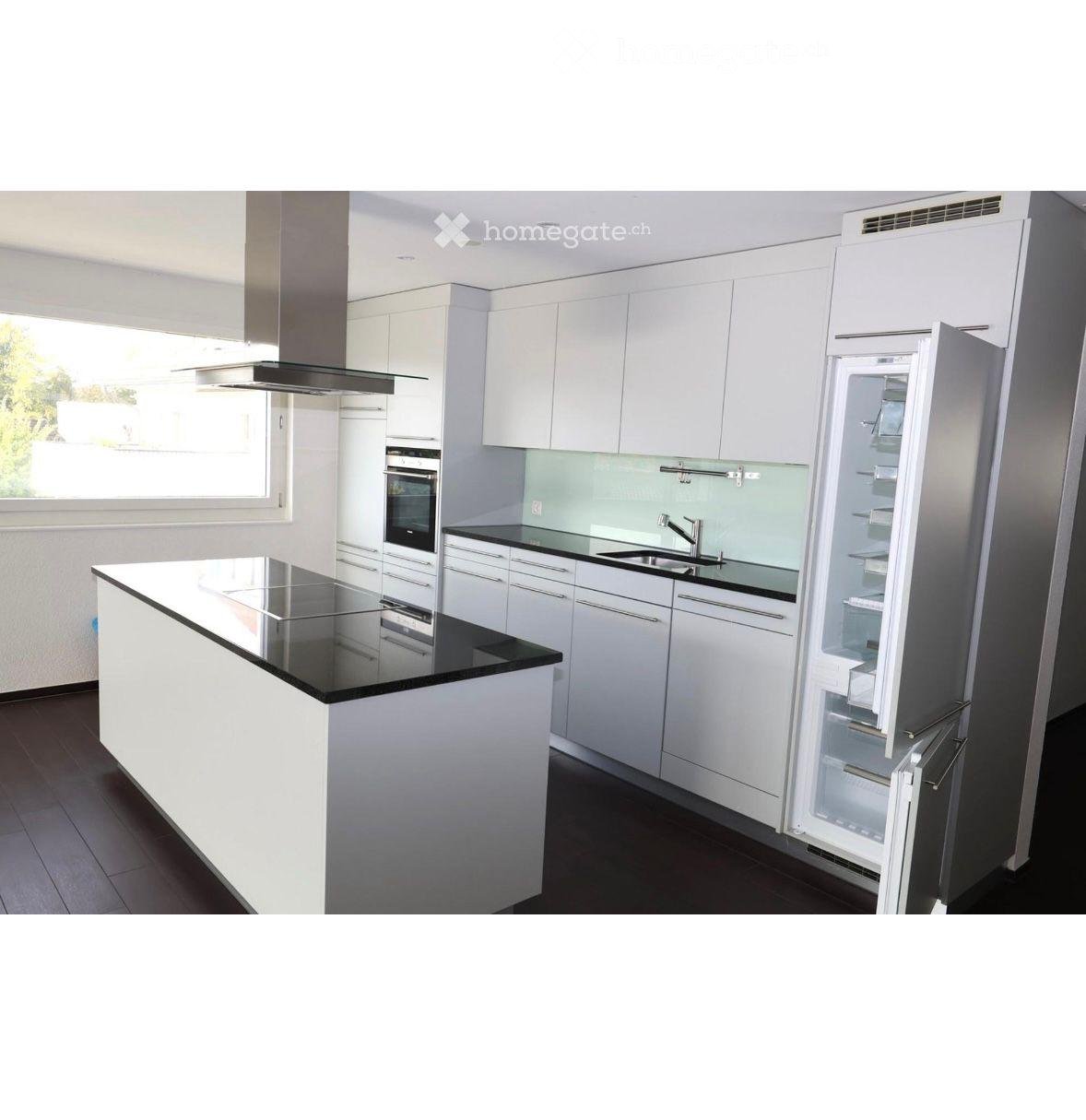 Modern kitchen with white cabinets, black countertops, stainless steel appliances, and an island with a black countertop.