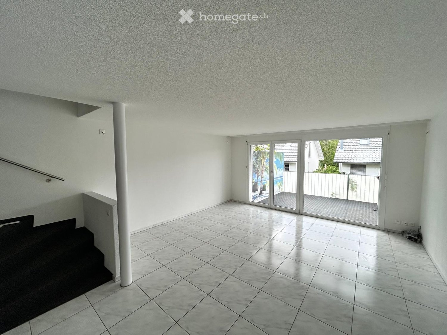 Empty hallway with tiled floor, white walls, and a sliding glass door leading to an outdoor area.