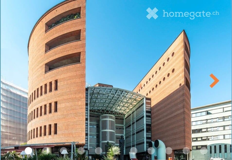 Modern building with curved brick facades, glass entrance, and geometric design.