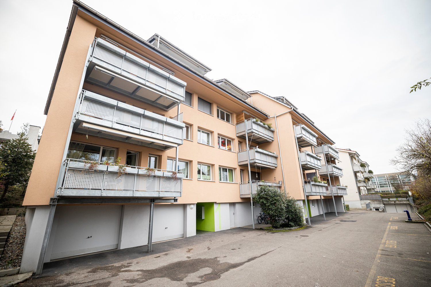 Multi-story residential building with balconies, garage, and modern facade.