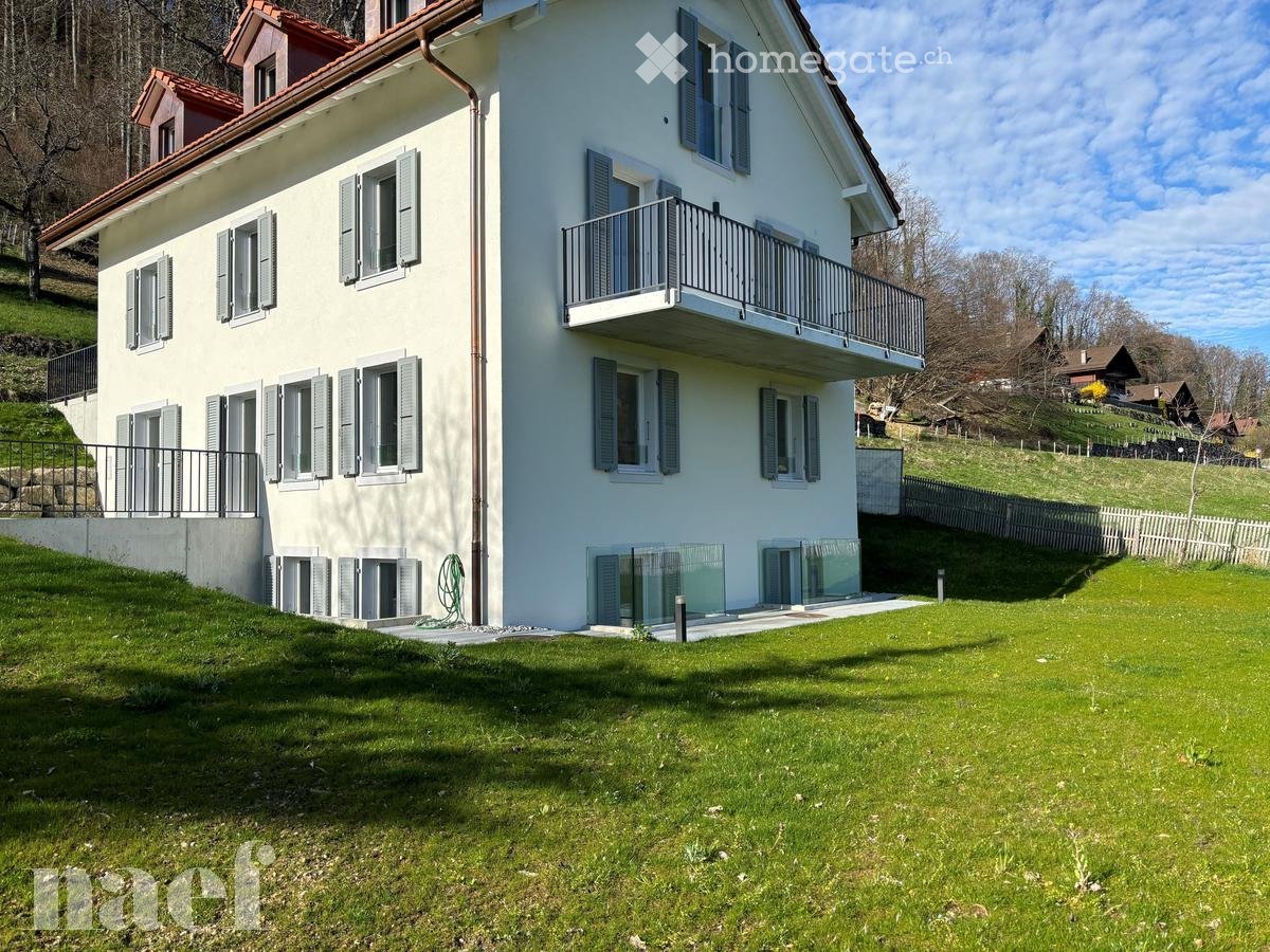 Two-story house with white exterior, multiple windows with shutters, balconies, and a well-maintained lawn.