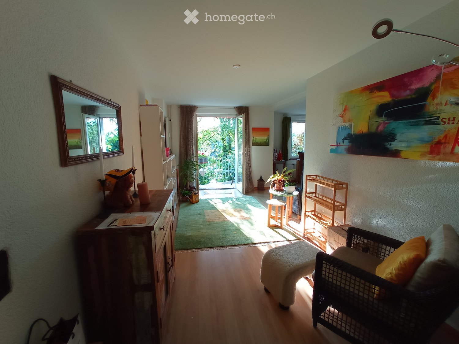 {"visible_features": [], "type": "Living room", "description": "wooden floor, beige walls, green rug, large window, outdoor patio, floor lamp, wooden cabinet, mirror, art piece, plant, shelves, stool, armchair, footstool, pillow, power outlet"}