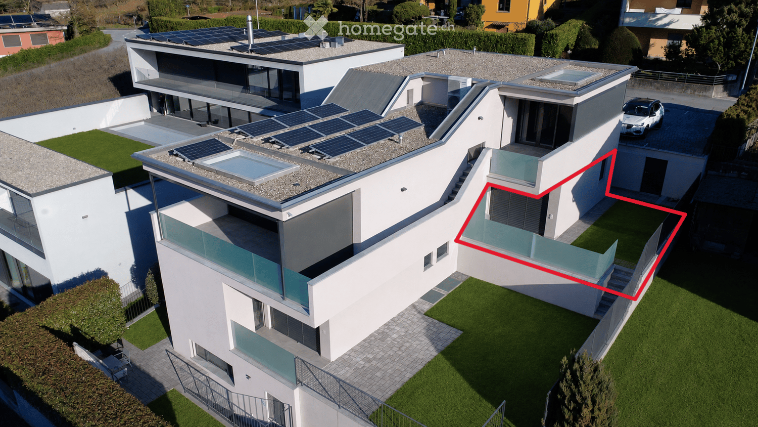 Modern two-story house with white exterior, solar panels on the roof, garage, and parking area.