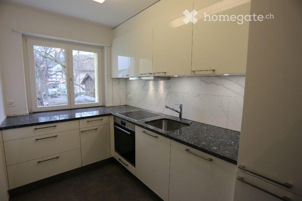 Modern kitchen with white cabinets, granite countertops, and stainless steel sink and faucet.