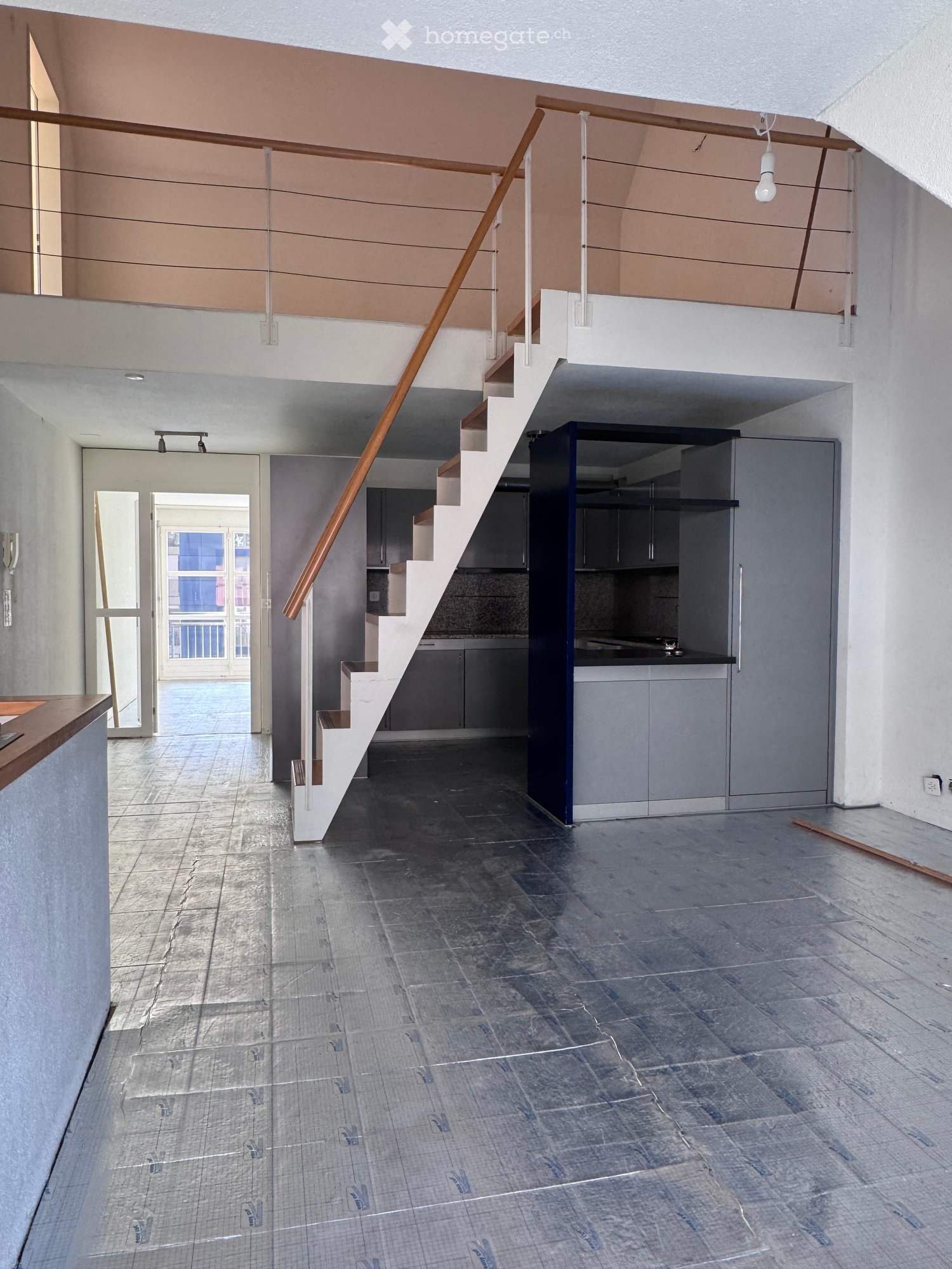 Empty interior space with a staircase leading to an upper level, modern grey cabinets, and a tiled floor. No furniture or personal items are present.