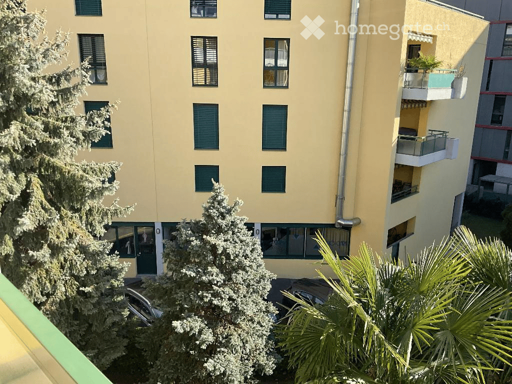 Multi-story residential building with balconies, green shutters, and parking area below.