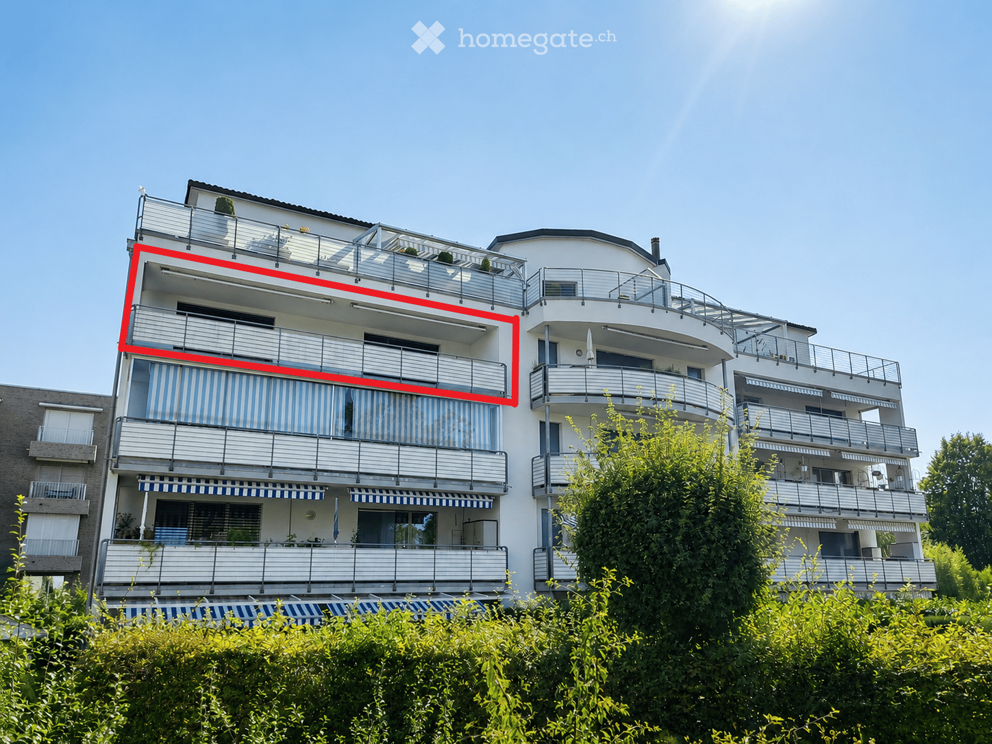Multi-story residential building with balconies, striped awnings, and modern railings.