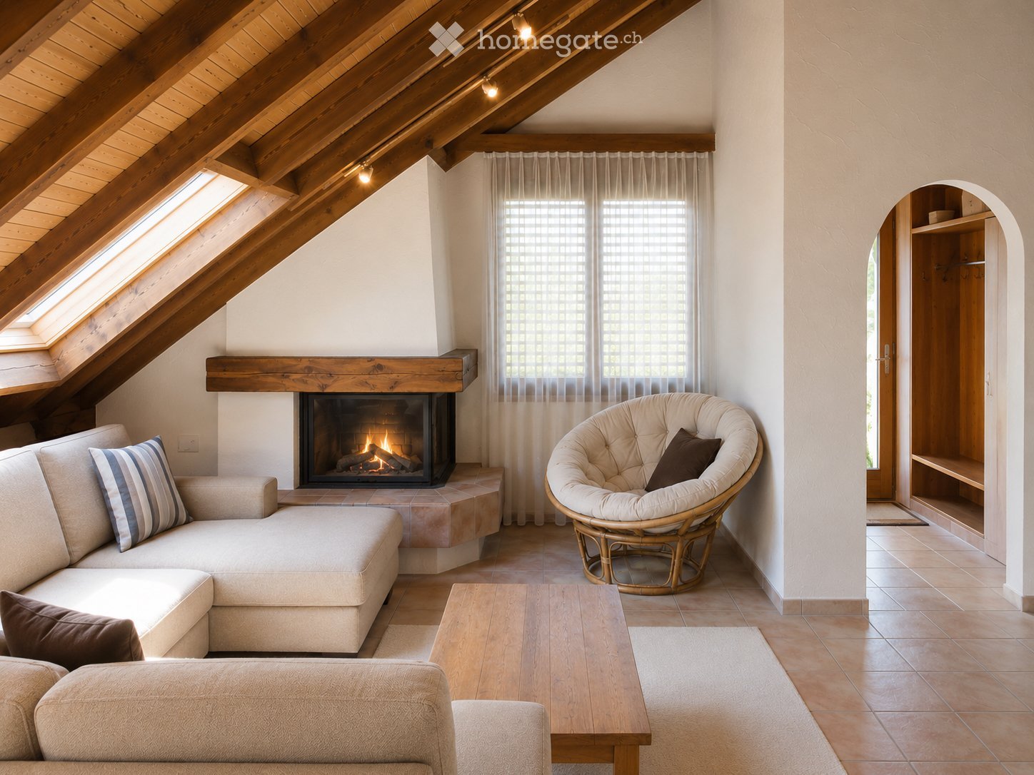 Cozy living room with exposed wooden beams, a fireplace, a sectional sofa, a wicker chair, and a coffee table.