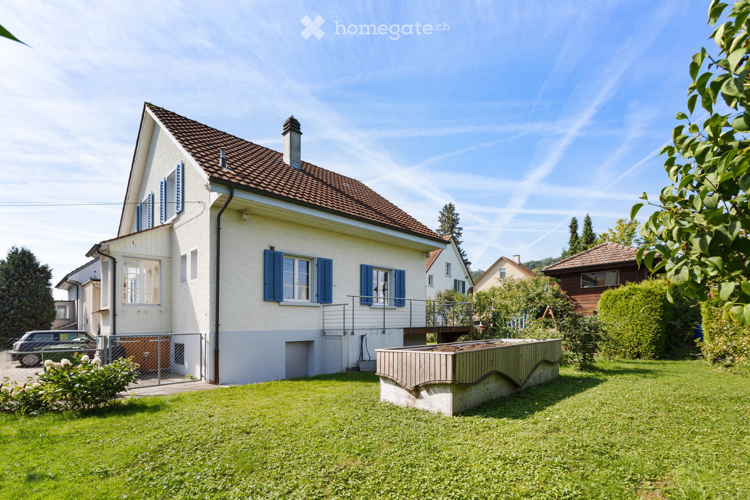 2 story house, white walls, brown roof, blue shutters, balcony, garden, car parked in front