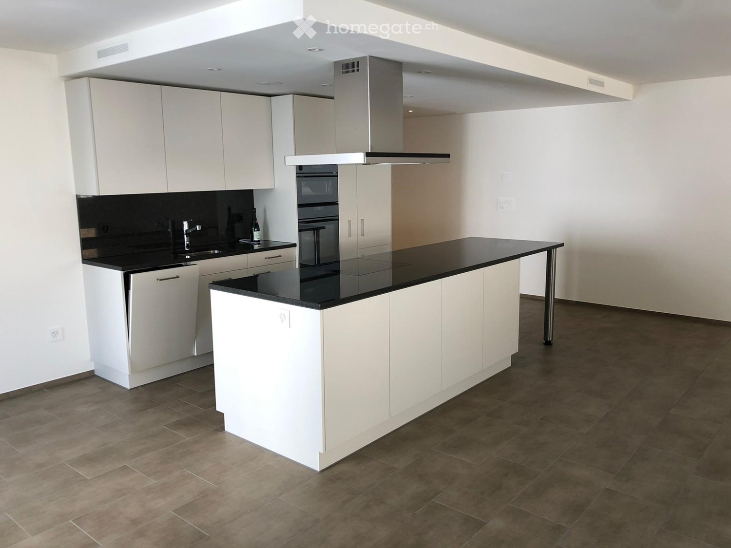 Modern kitchen with white cabinets, black countertops, stainless steel appliances, and a central island.