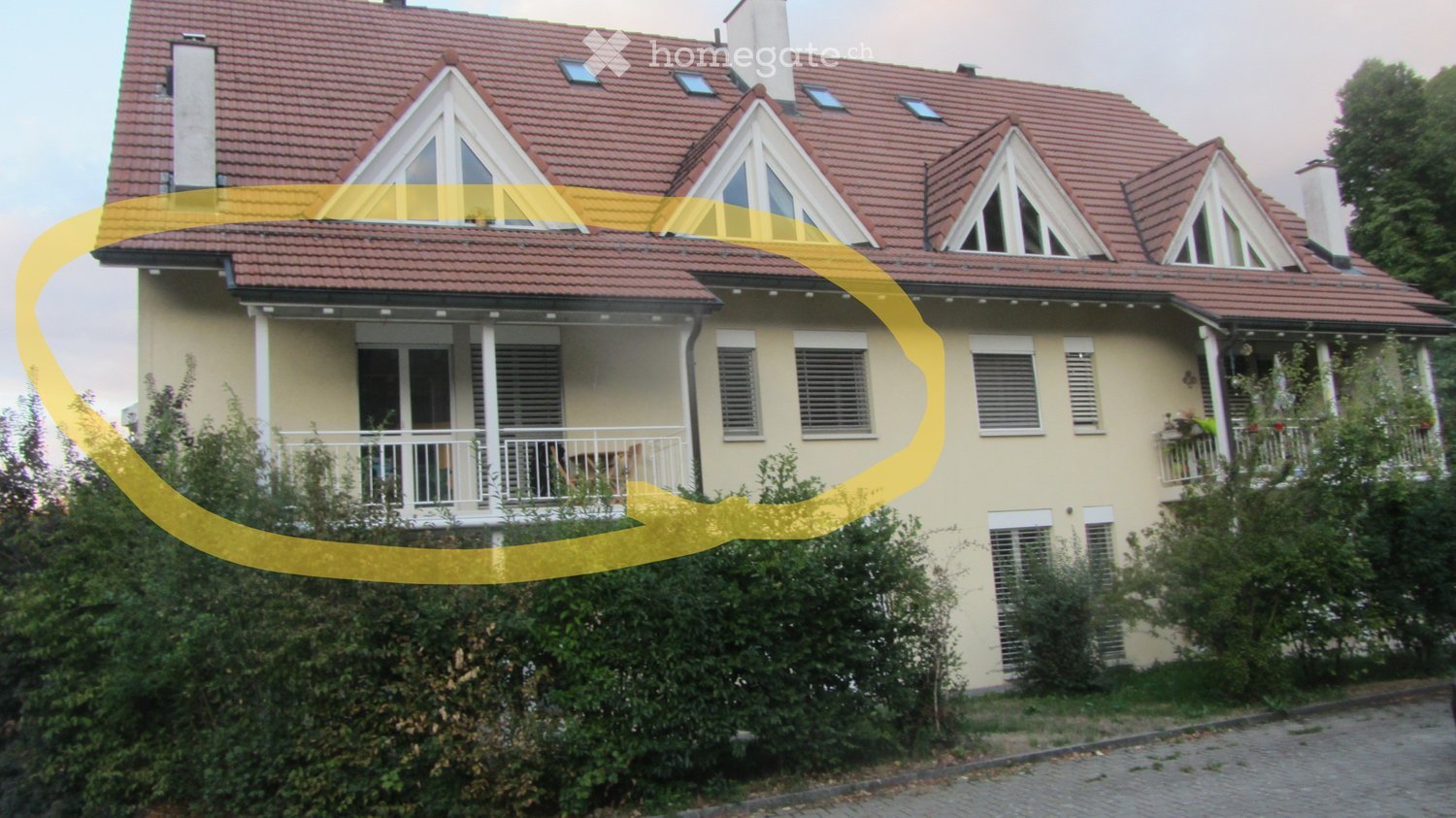 Two-story house with red-tiled roof, multiple dormer windows, and a balcony on the first floor.