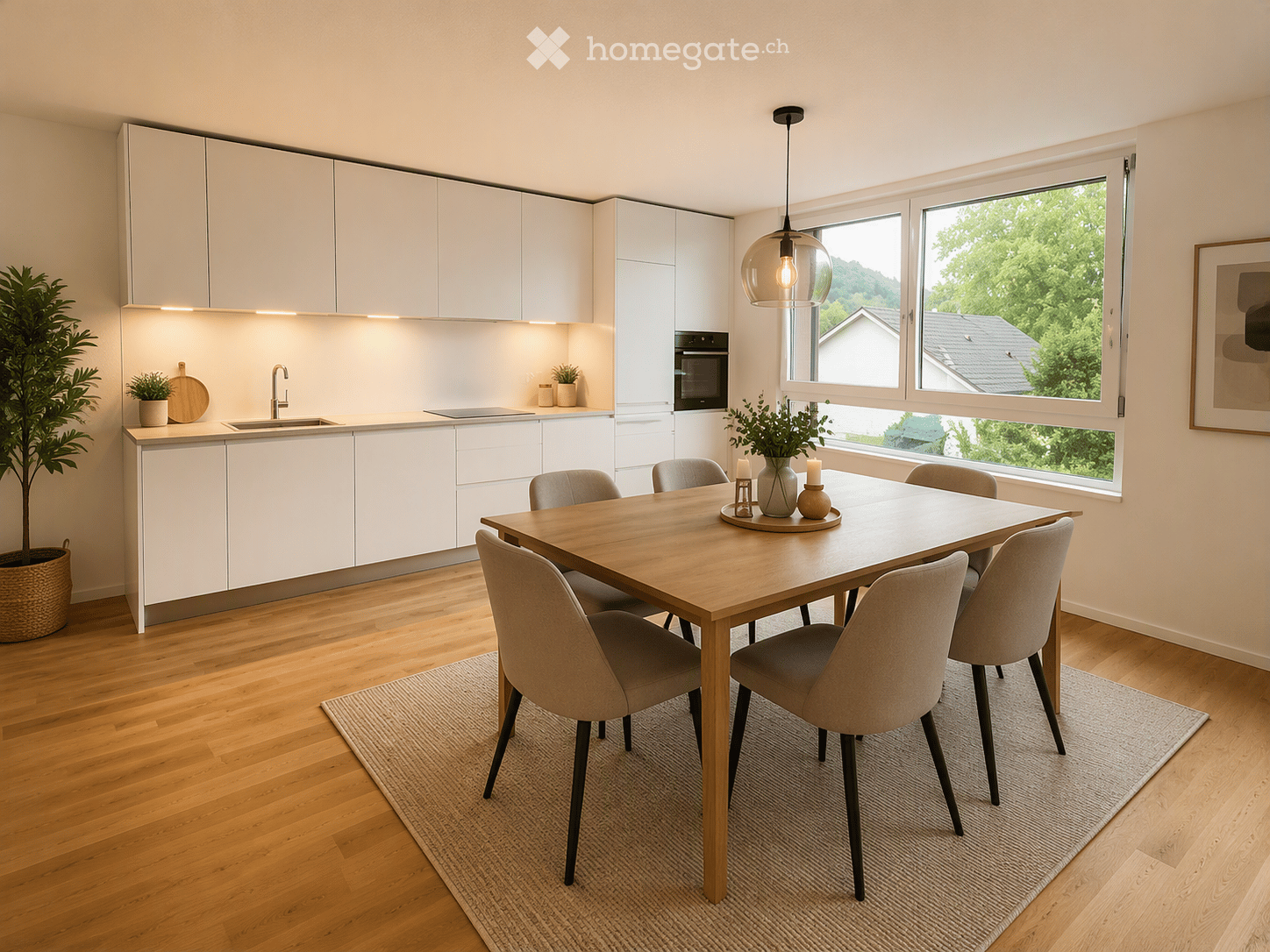 Modern kitchen with white cabinets, a central island, a dining table with six chairs, pendant light, and large windows overlooking greenery.