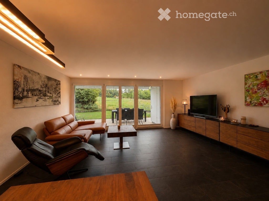 Modern living room with dark tiled flooring, large glass doors opening to a green outdoor area, leather sofa, coffee table, TV stand, and decorative vases.