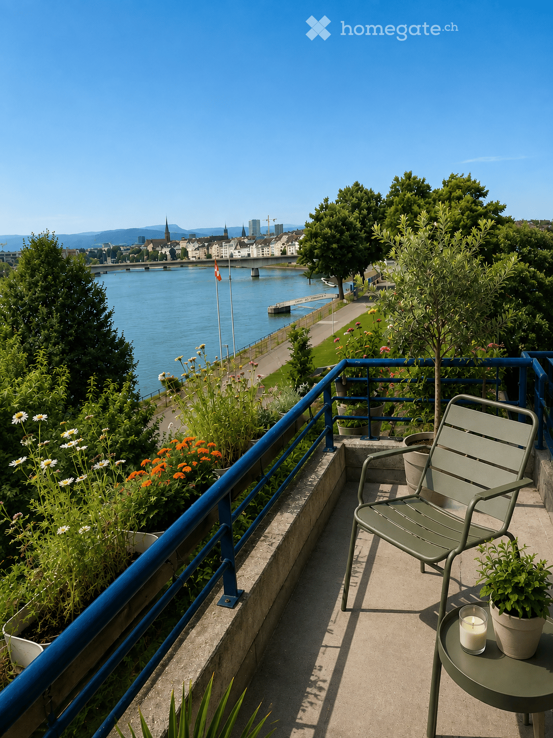 Balcony with a view of a river and cityscape, featuring a green chair, small table with a candle, and potted plants.