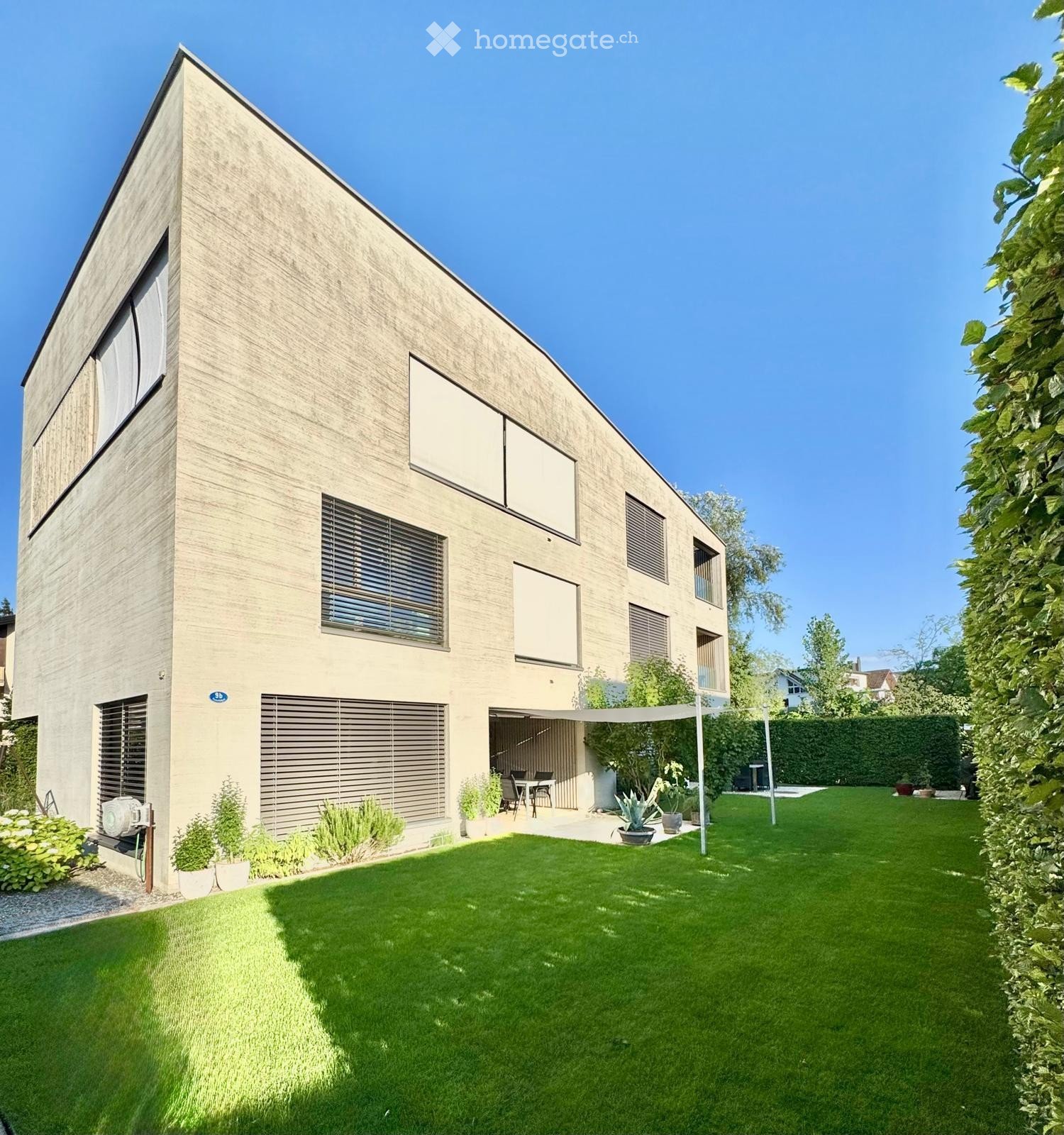 Modern two-story house with a sleek, contemporary design, featuring large windows, a covered patio area, and a well-maintained lawn.