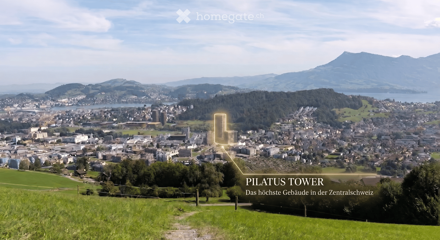 A panoramic view of a cityscape with the Pilatus Tower highlighted, surrounded by green fields, forests, and distant mountains.